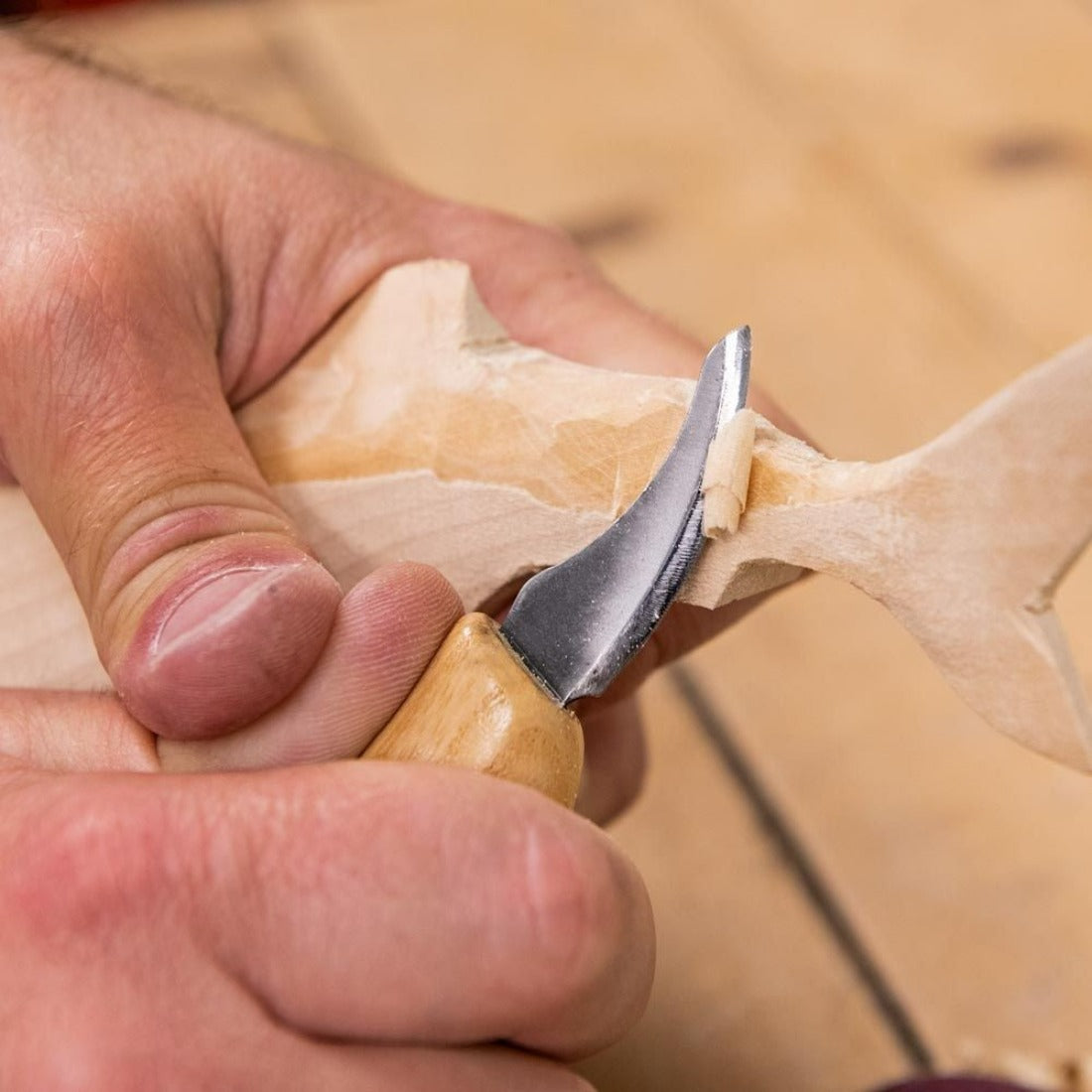 close up image of the carver using the smallest detail knife carving the tail of the fish