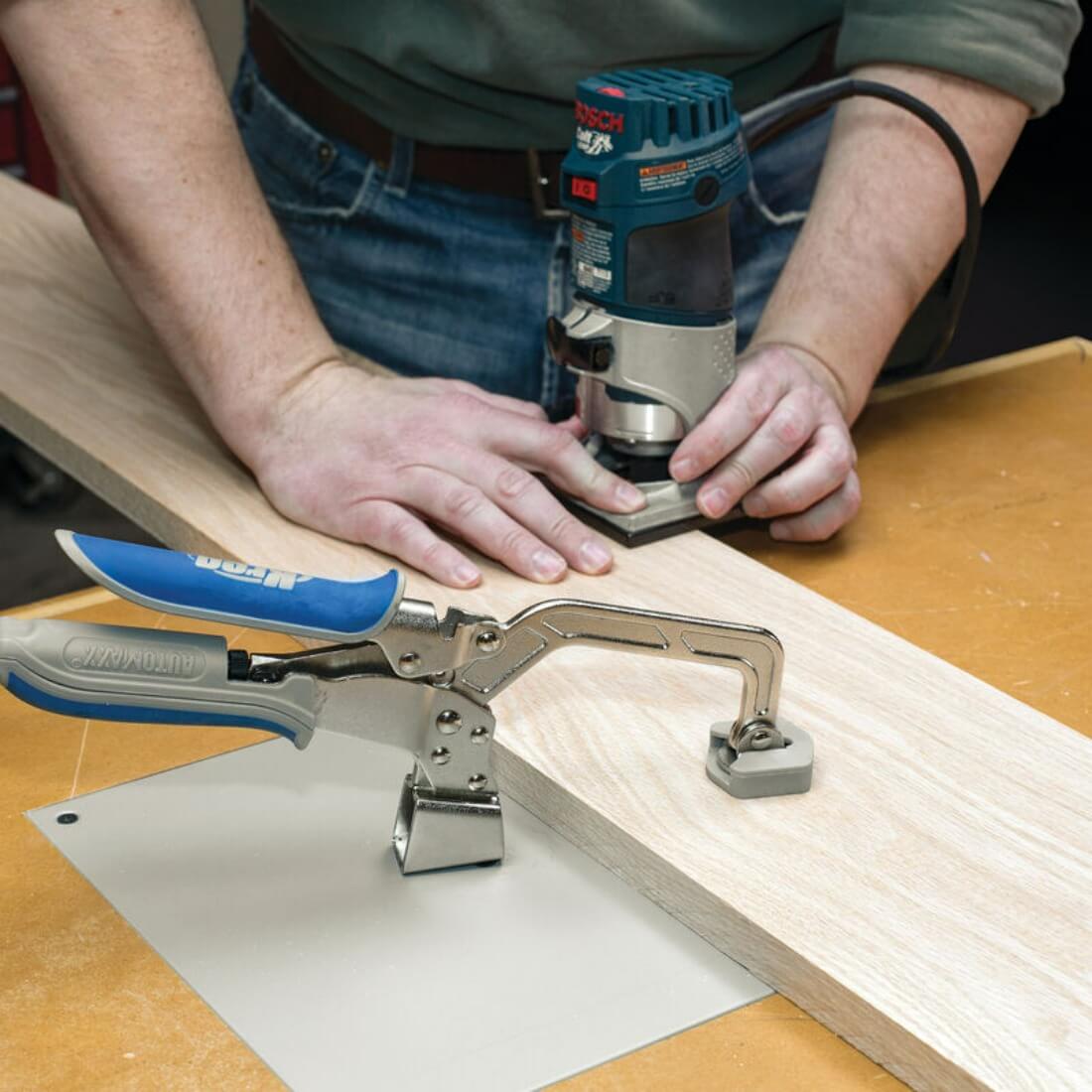 Kreg Automaxx 3 inch Bench Clamp is shown clamping a plank of wood being routered