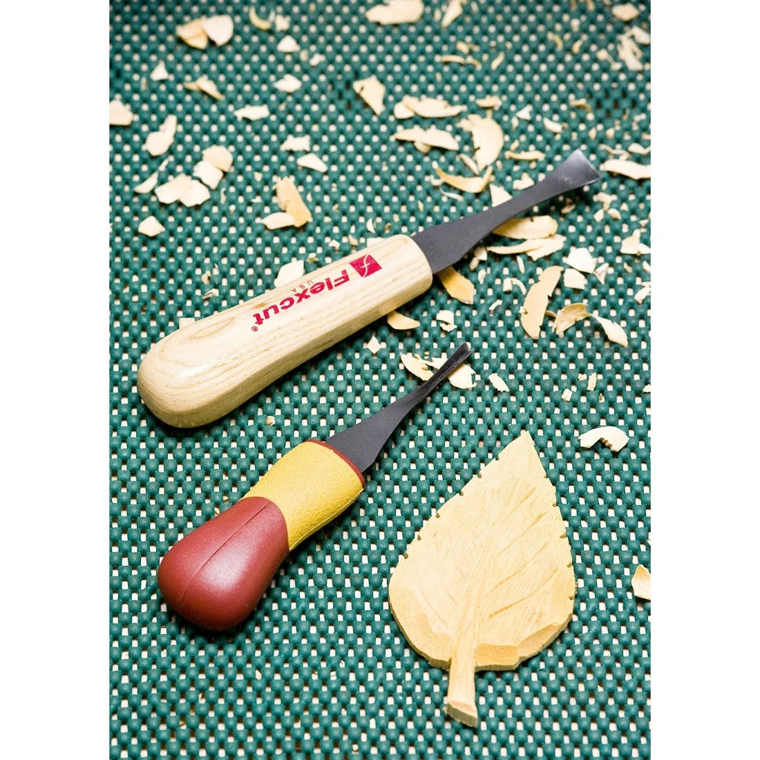 image showing the finished carving work of a leaf carved from basswood. Two knives shown are a gouge and V shaped gouge using the handles from the set.