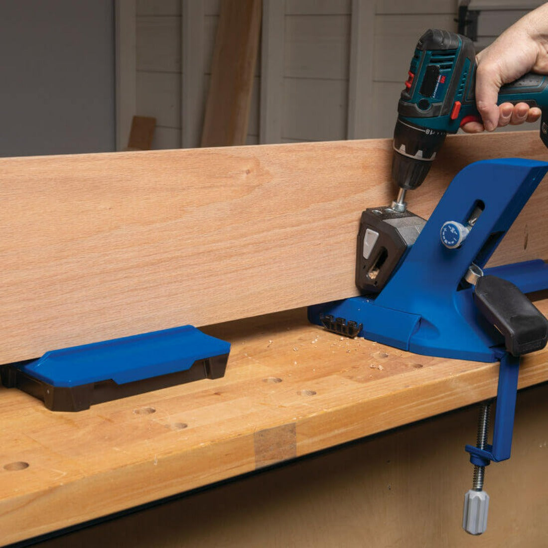 image shows a 720 jig fixed to bench with g clamp. Wings of docking station supporting a long piece of timber while being drilled for pocket holes.