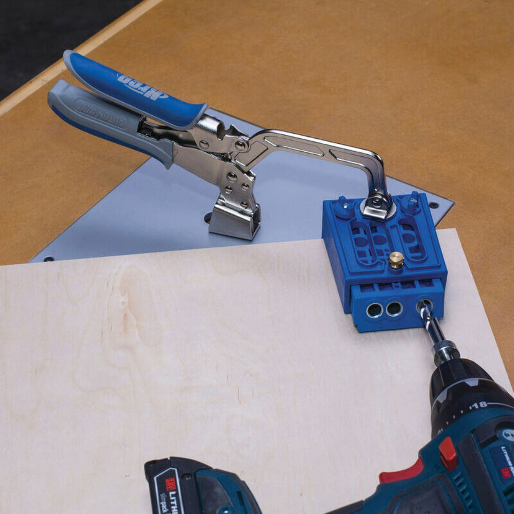 Kreg Heavy-Duty Bench Clamp System KBC3-HDSYS shown holding a pocket jig while user is drilling pocket holes in flat sheet