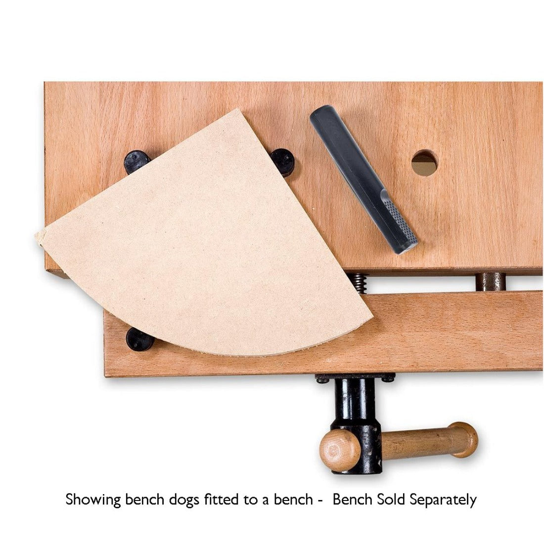 triangular shaped timber piece with one side as a curve being held on a bench with bench dogs. One bench dog in the vice, two on the bench  to hold the piece.